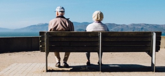 two elderly people sitting on a bench